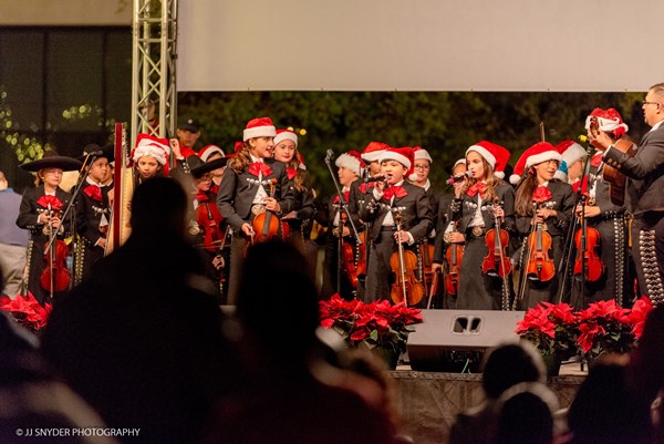 Students wearing mariachi clothing and Santa hats while performing on stage