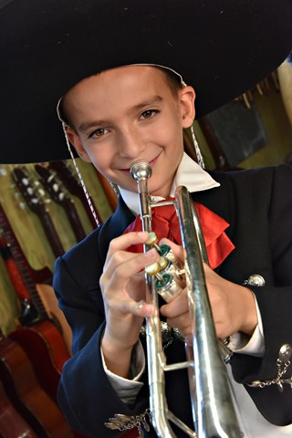 Student in mariachi clothing playing a trumpet