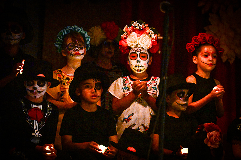Students in Dia de los Muertos makeup and outfits hold lights in their hands