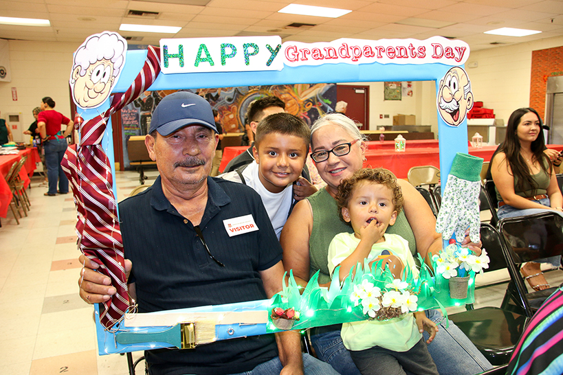 A man, woman and their two grandsons pose in a Happy Grandparents Day photo frame