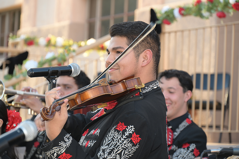 A teen boy smiles as he plays violin