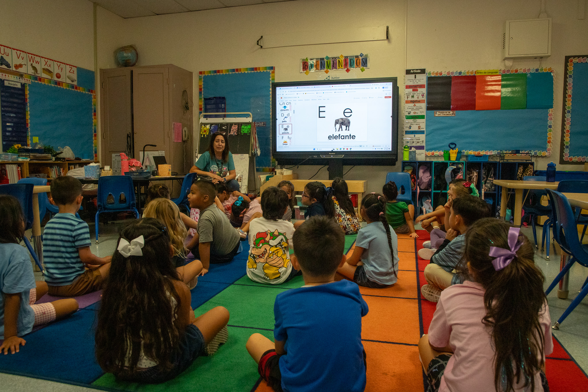A teacher talks to her students as they sit on the floor
