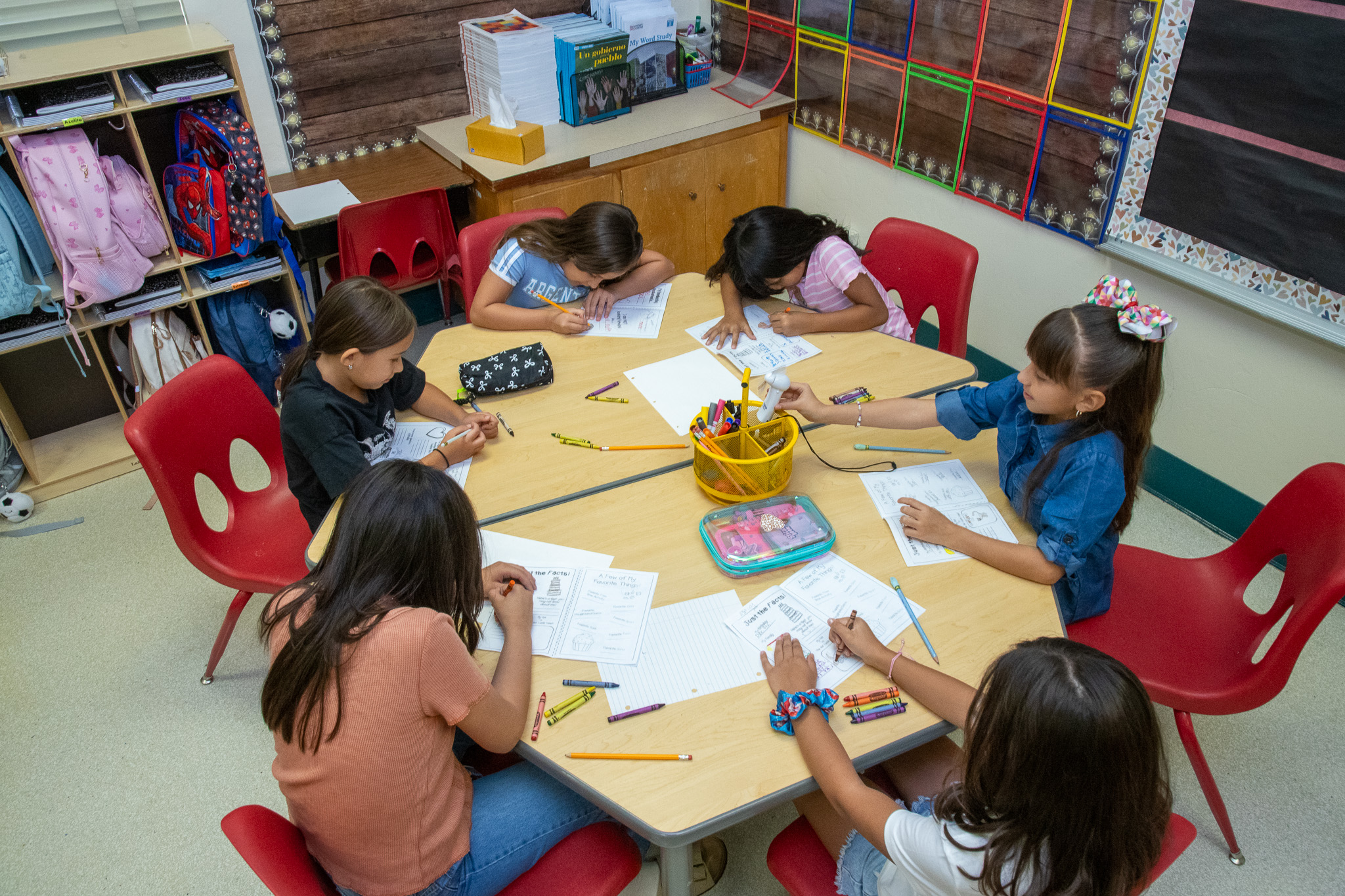 A group of girls sitting around a table in the classroom working on an assignment