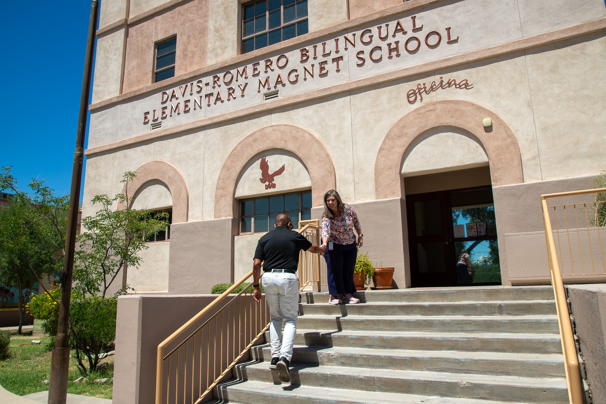 Dr Trujillo shakes a woman's hand as he walks up the stairs to the school