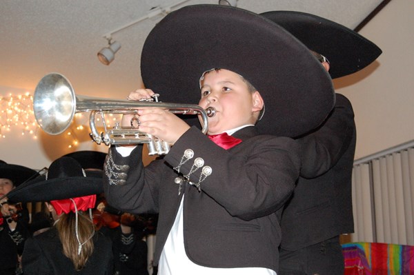 Student dressed in Mariachi clothing playing a trumpet