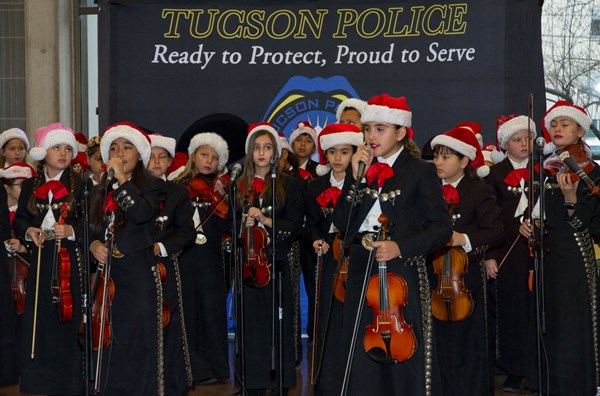 Students dressed in mariachi clothing and Santa hats singing on stage