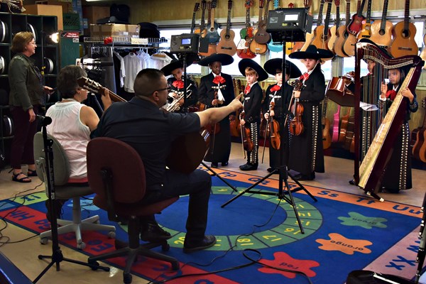 Teachers instructing students dressed in mariachi clothing holding instruments