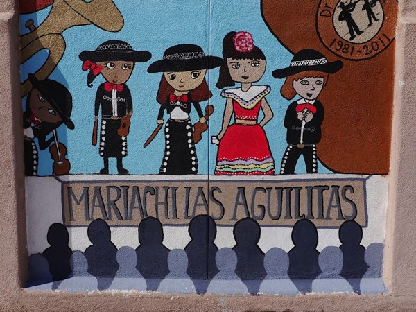 Mural of students dressed in mariachi and Mexican dancing dresses with the words "Mariachilas Aguilitas"