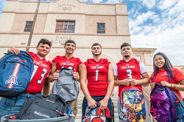 Tucson High School Football players standing outside Davis School holding bookbags 