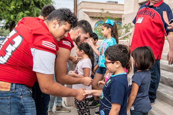 Tucson High School Football players passing out bookbags to Davis students 