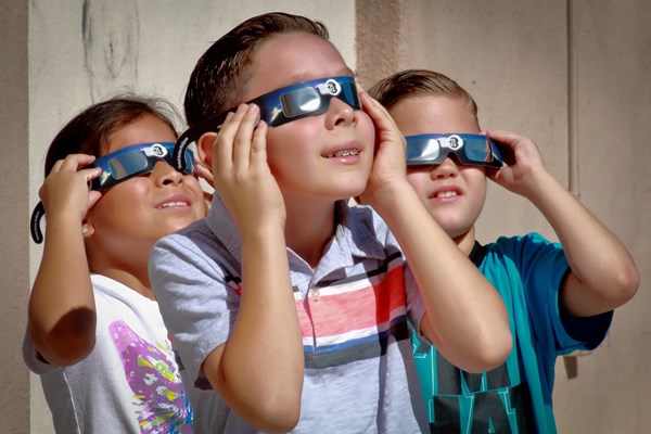 Students wearing eclipse viewing glasses looking up