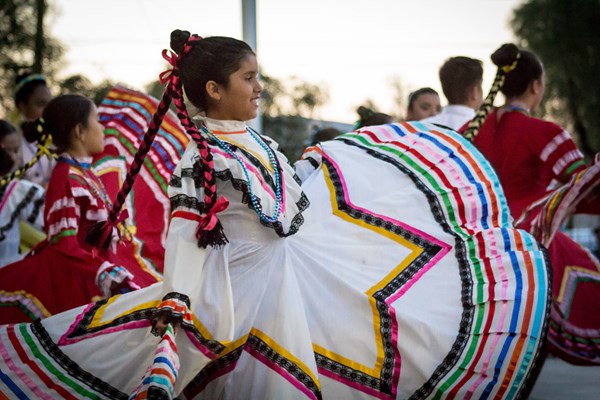 Students dressed in Mexican dancing dresses performing outside