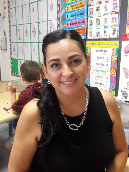 TA Alina Martinez smiling in a busy classroom
